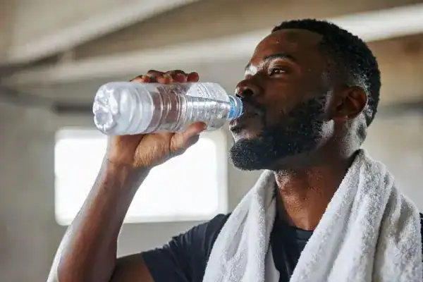 Image of man drinking water to improve hydration Lowestoft after work out.